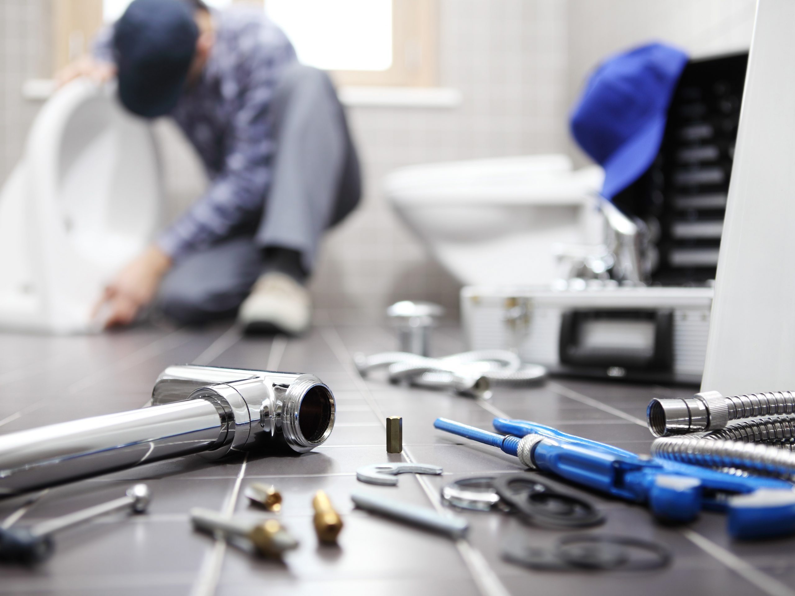 Photo of a plumber working on a bathroom with tools laid out on the floor