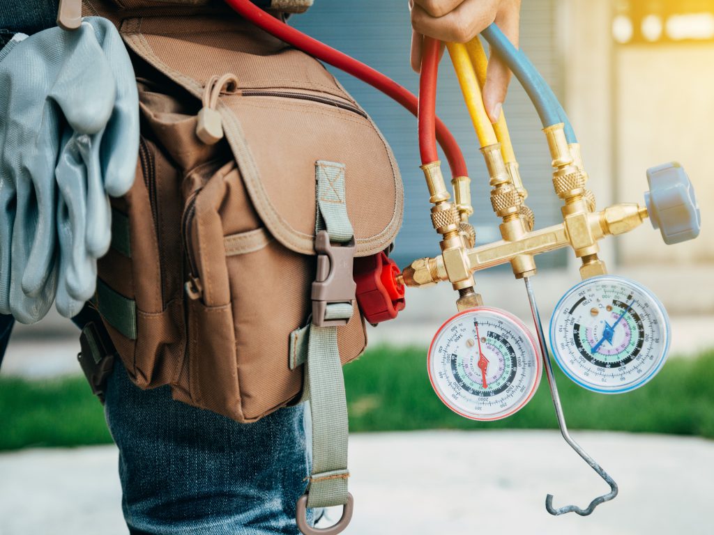 Photo of a contractor wearing a tool belt and holding a temperature guage