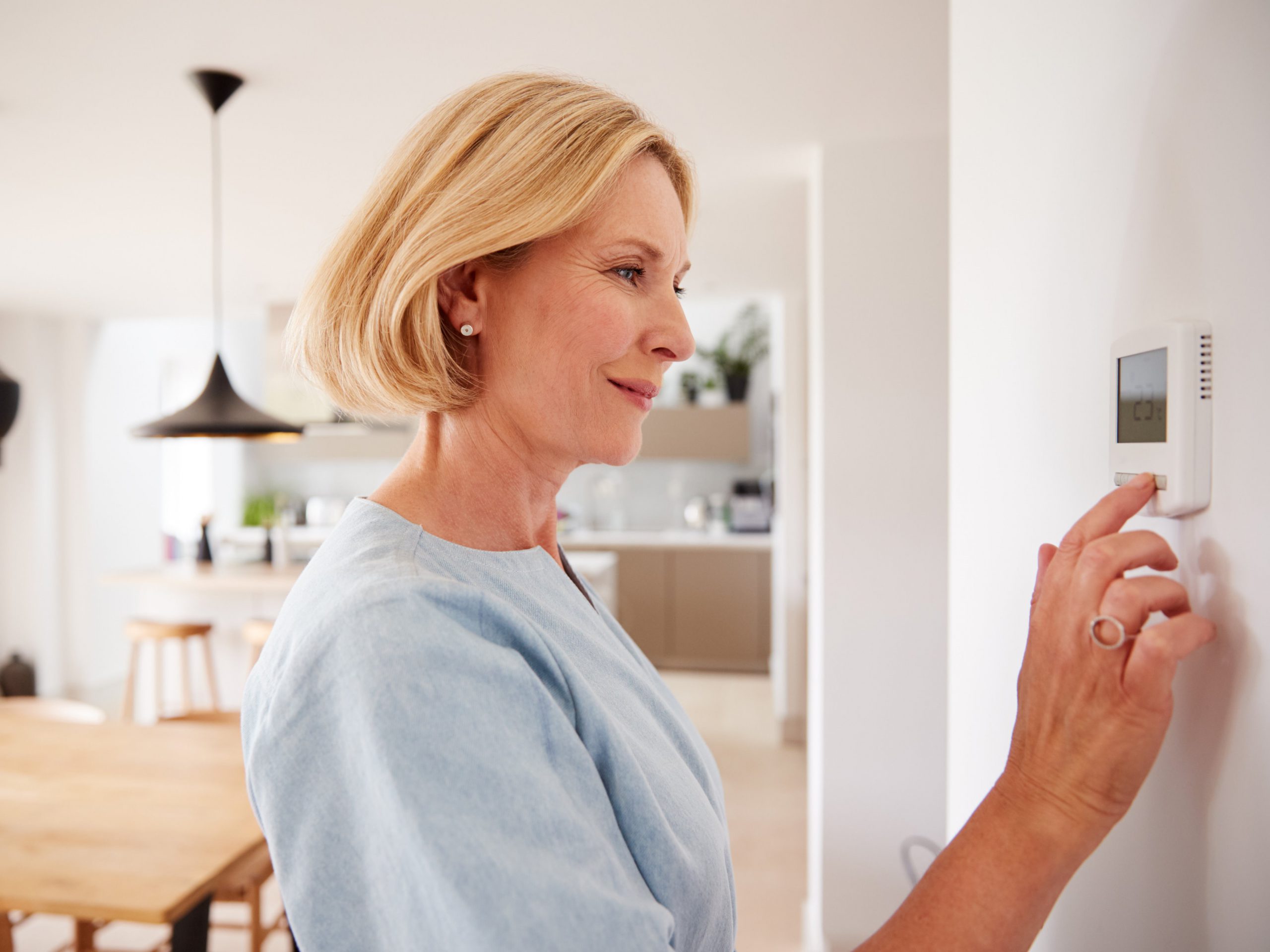 Photo of a woman adjusting a thermostat on her Missoula, Montana HVAC system